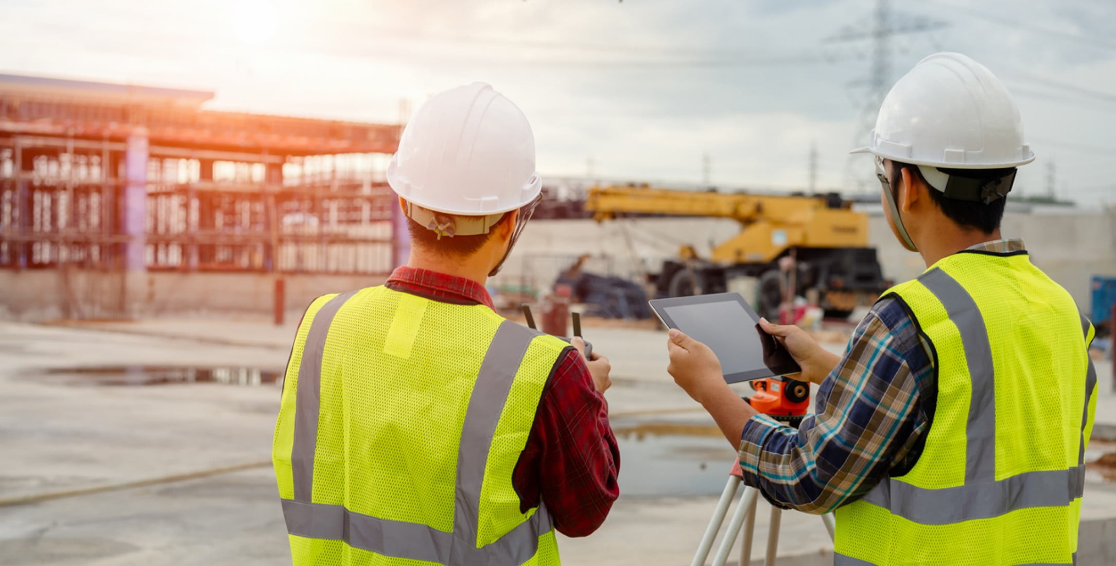 Two construction workers using a drone on a construction site.