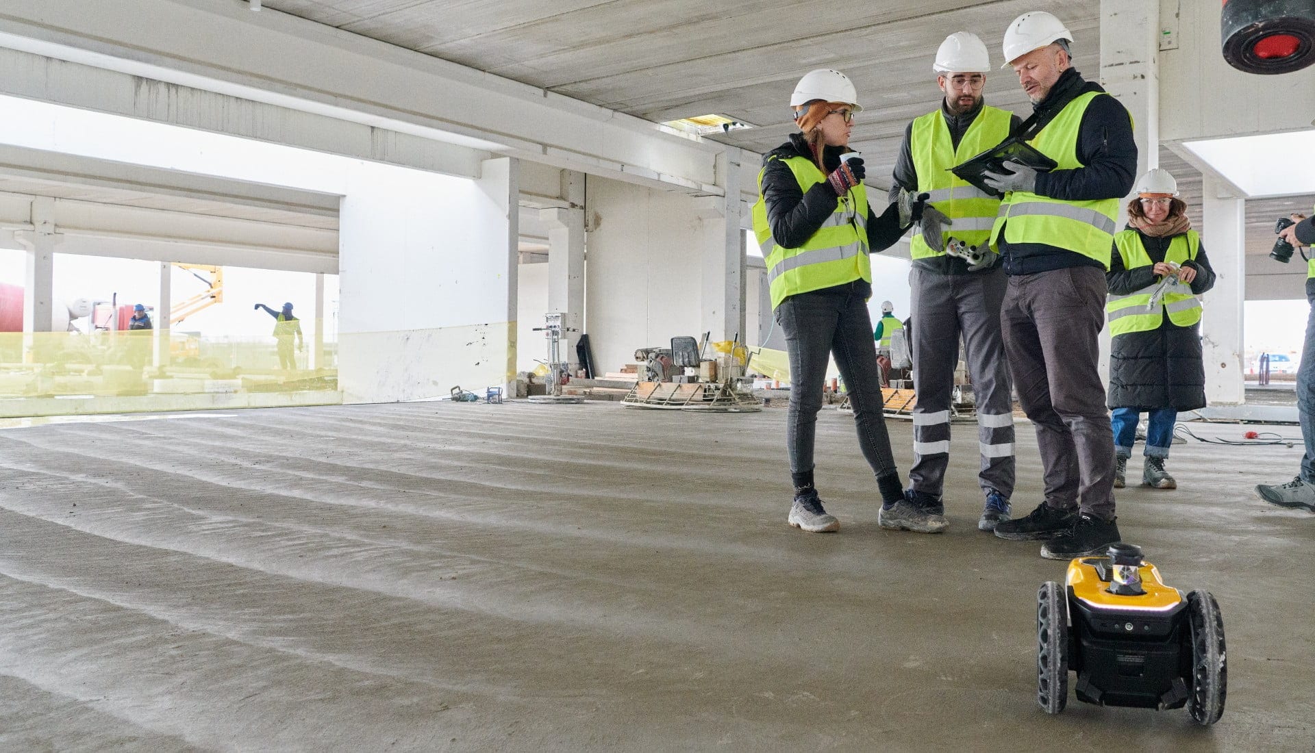 A group of construction workers looking at a tablet on a construction site.