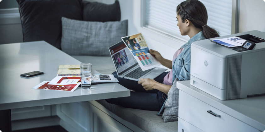 A woman checking some prints holding an HP Laptop at home.