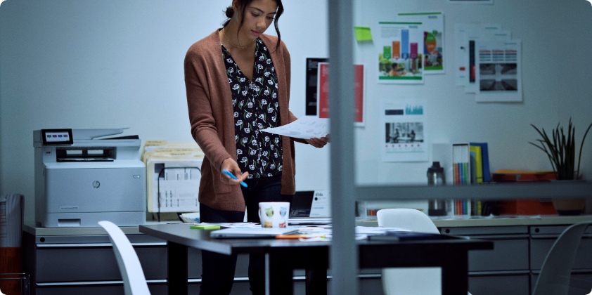 A woman looking at some papers near an HP Wireless Printer.