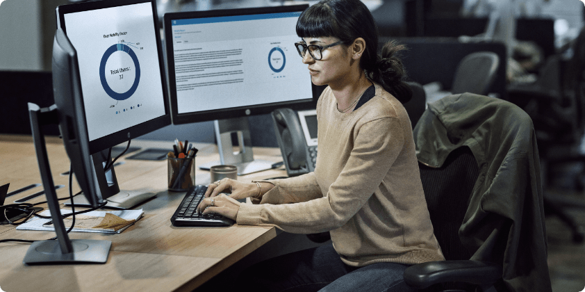 A woman looking at some data on her HP Monitors in her office.