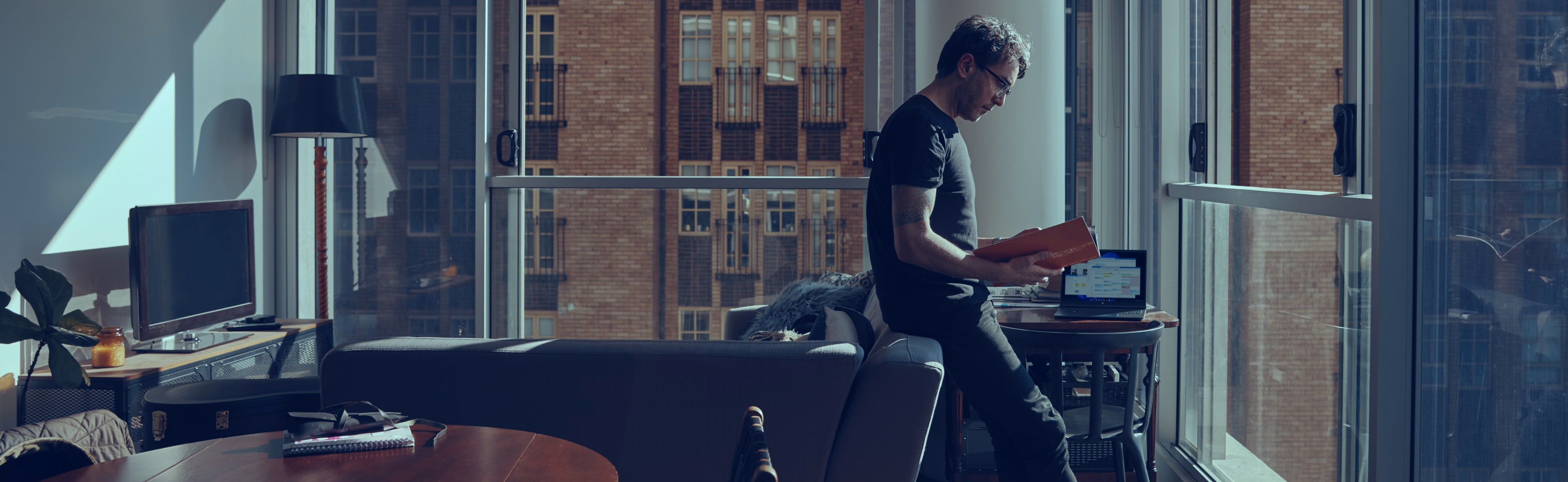 Man reading reports with HP Laptop beside him