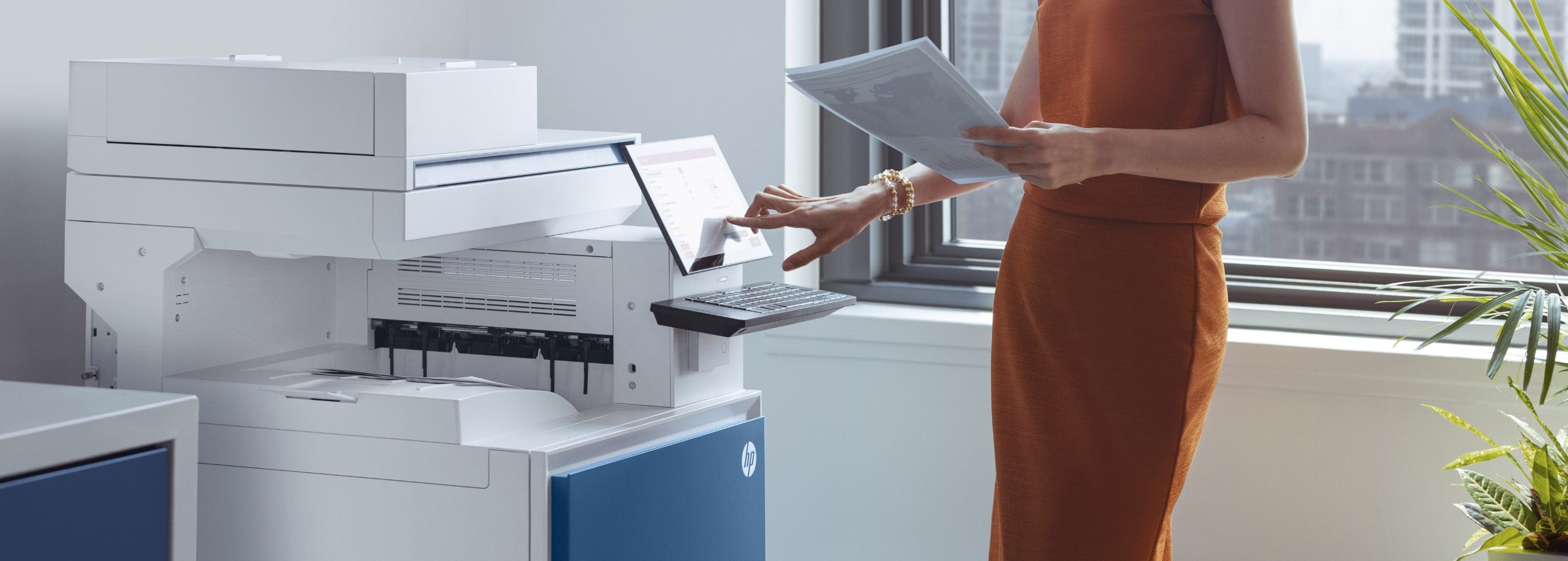 Female office worker looking at printed documents standing in front of HP LaserJet Enterprise MFP