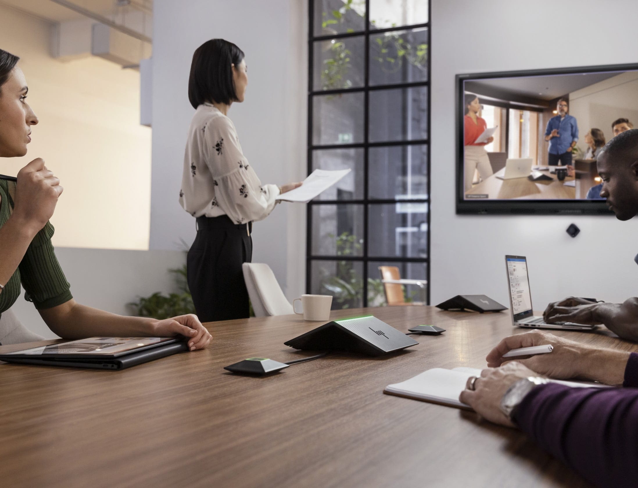 Professional people in a conference room, at a conference table, looking at a video call