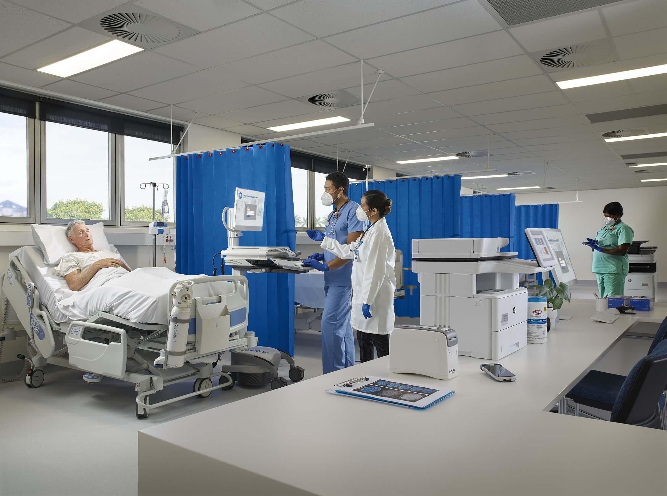 Hospital urgent care with patient in bed, two physicians, and HP LaserJet printer in foreground