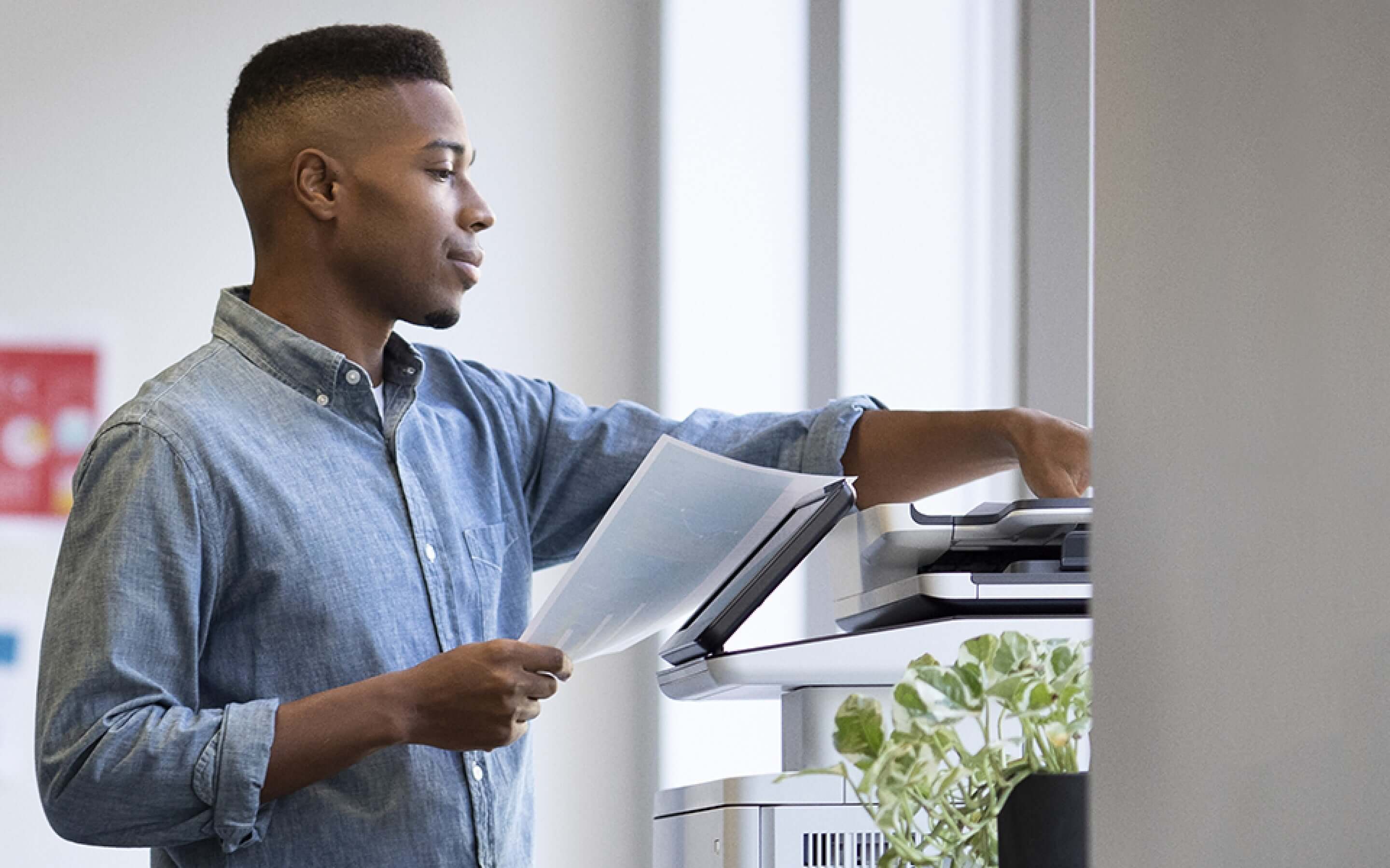 Uomo in un ufficio di fronte a una stampante HP LaserJet con documenti stampati in mano