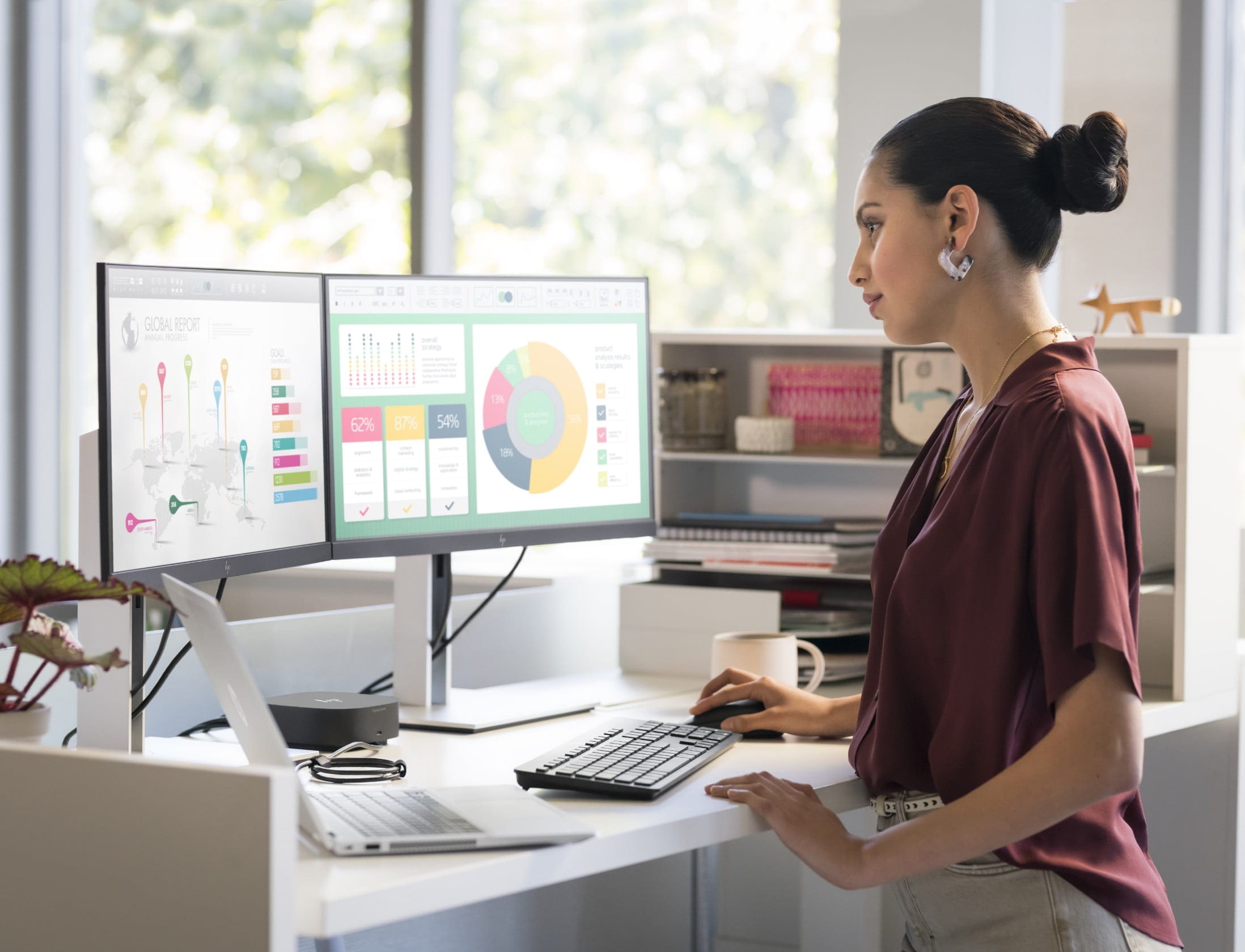 Professional woman standing at office desk looking at two HP monitors