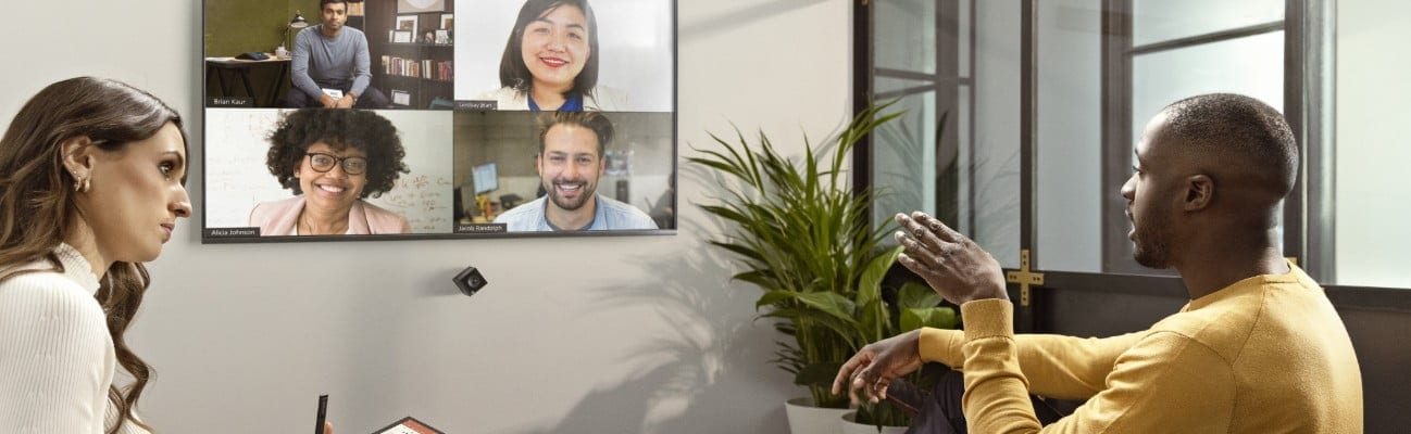 Two people having a virtual conference using an HP Presence Room Assistant device in a conference room.