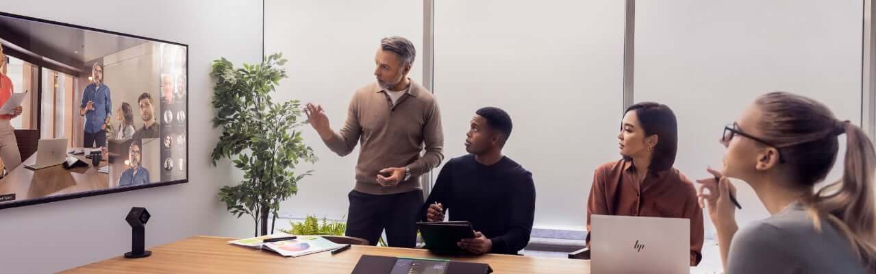 Employees having a business conference video call on a screen monitor in a meeting room.