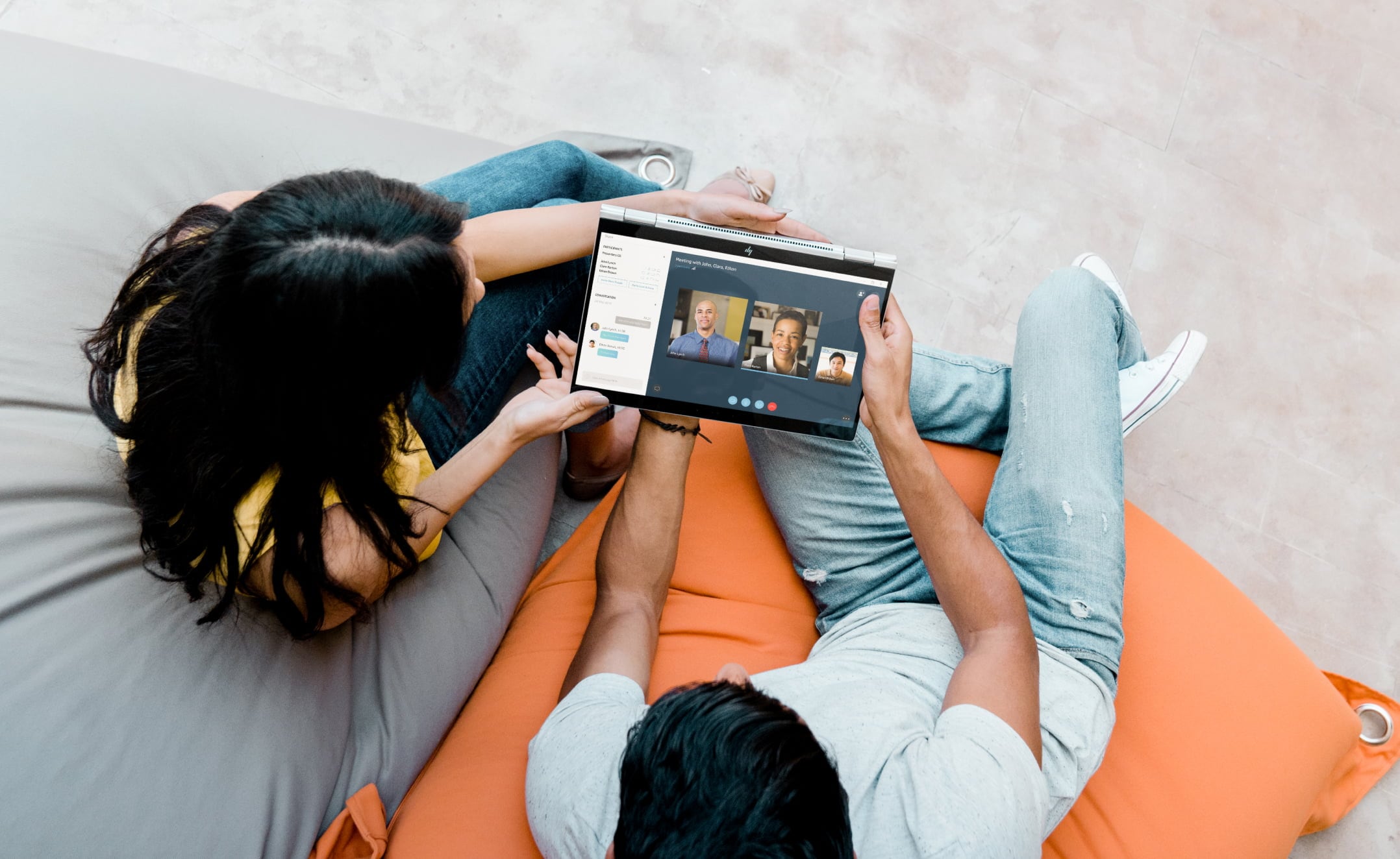 Two people work around HP laptop on couch