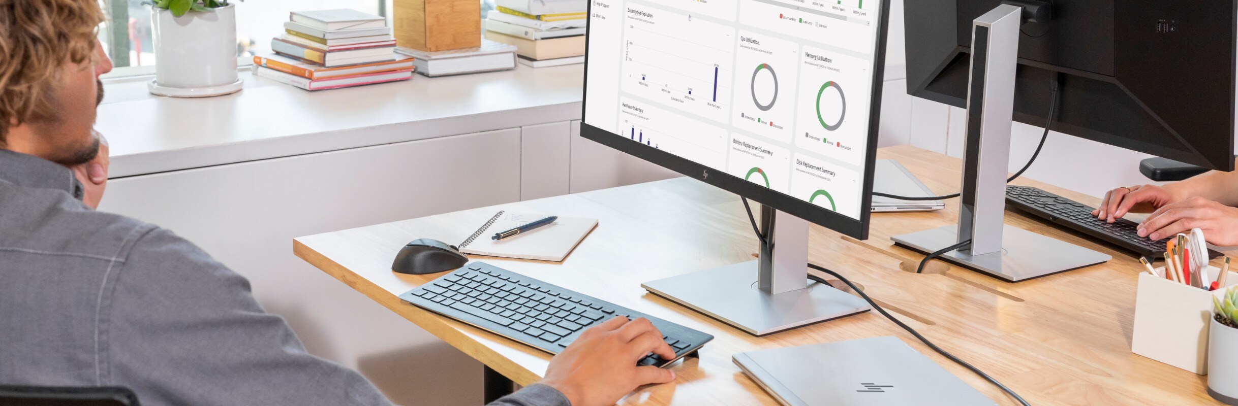 A man looking at an HP monitor that has an analytics dashboard on the screen