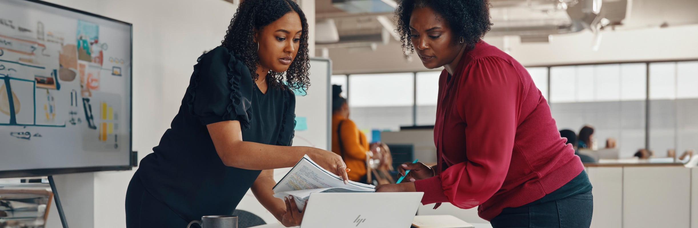 Two women working in an office with a laptop