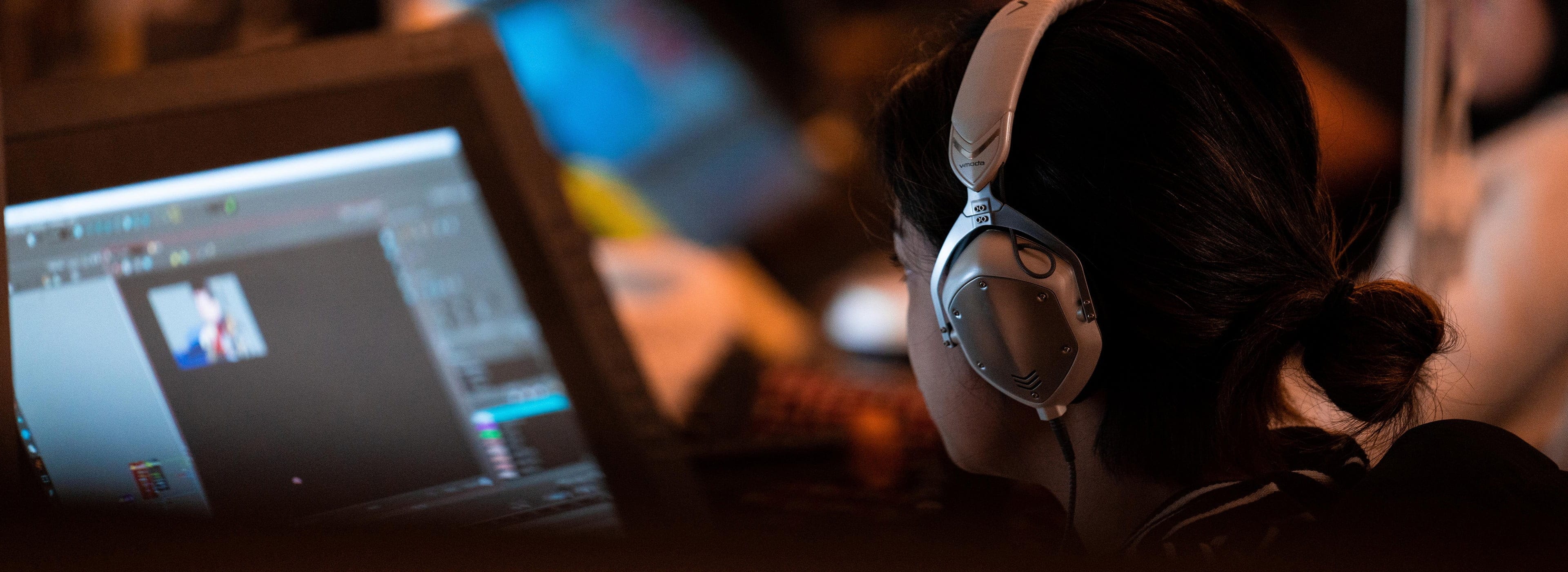 Close view of person wearing headphones while looking at monitor