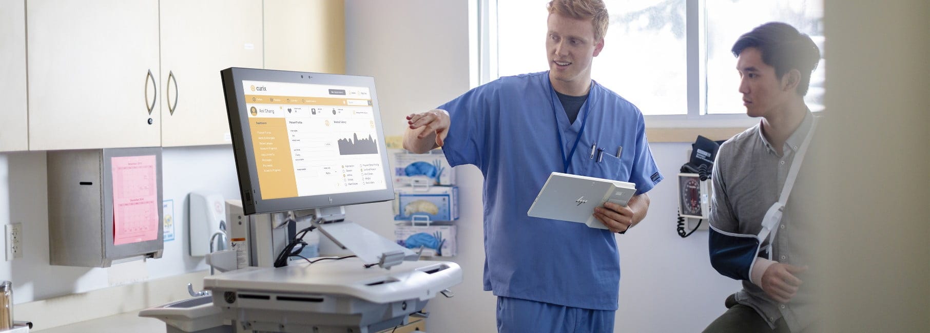 Doctor holding an HP Engage system while explaining to a patient some information displayed on an HP monitor