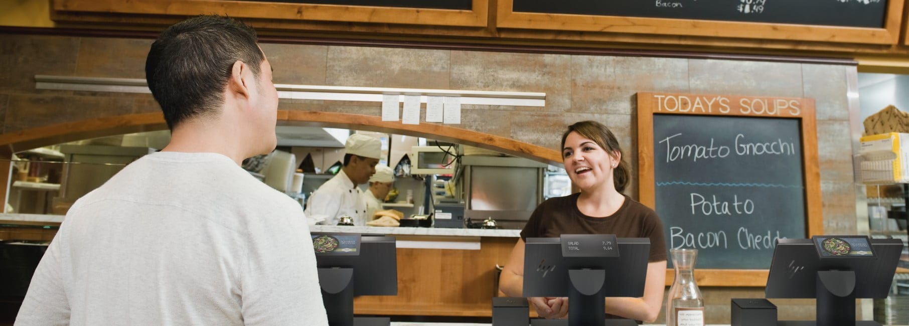 Restaurant worker taking an order from a customer, HP Engage One system is at the checkout counter