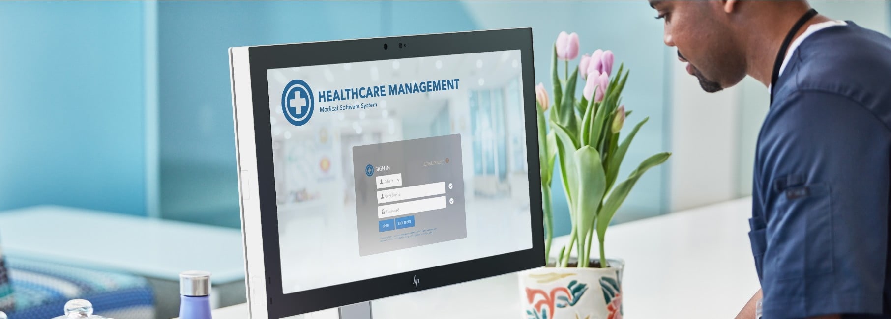 Male nurse is logging into the hospital database using an HP Engage One system