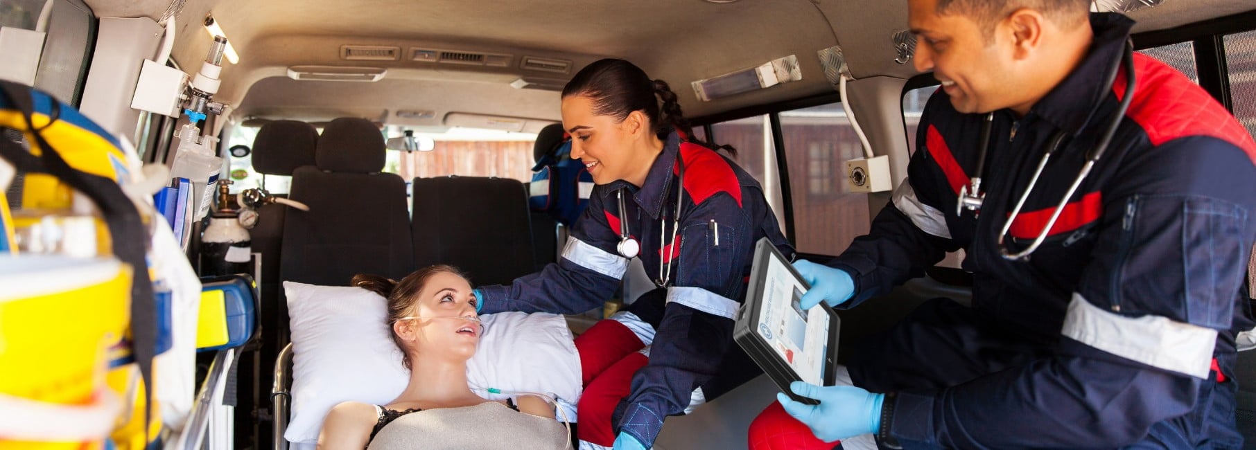 Paramedics talking to patient in an ambulance, one of them is using the HP Engage Go system in tablet mode