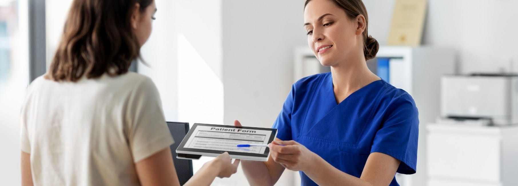 Nurse handing an HP Engage Go system in tablet mode to a patient to fill out an information form