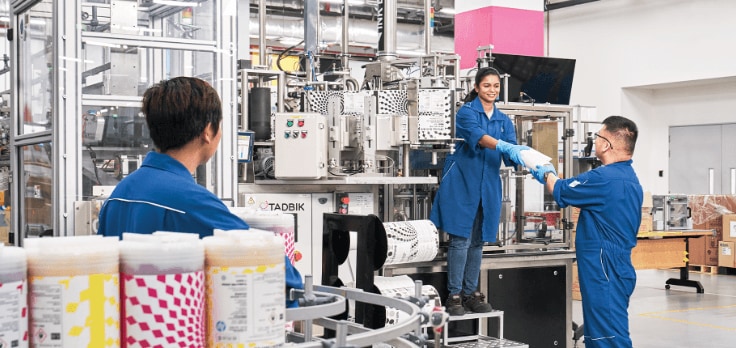 Three people working inside a factory.