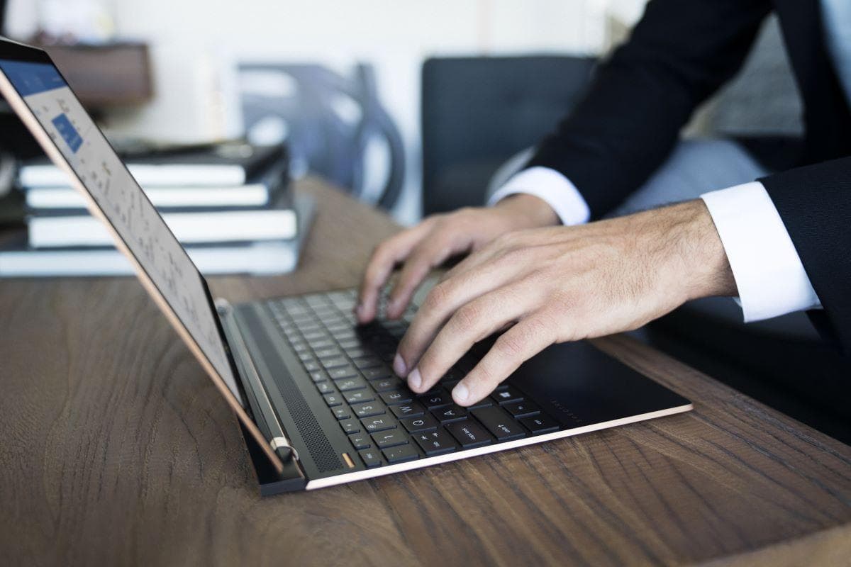 Close-up view of a businessman's hands typing on a slim HP laptop keyboard