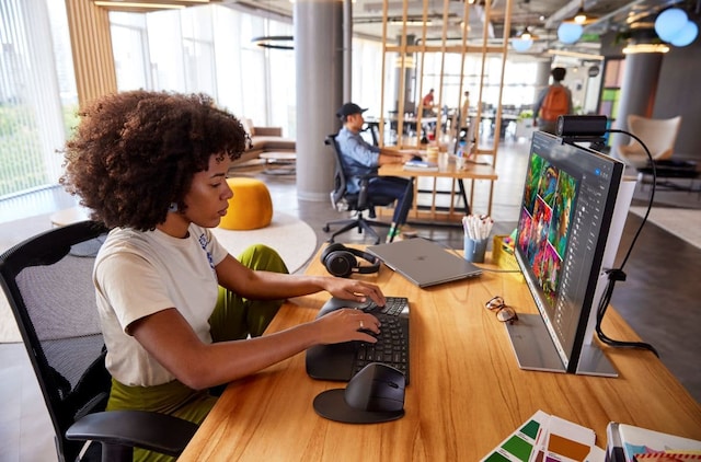 A woman with curly hair works at an HP desktop computer