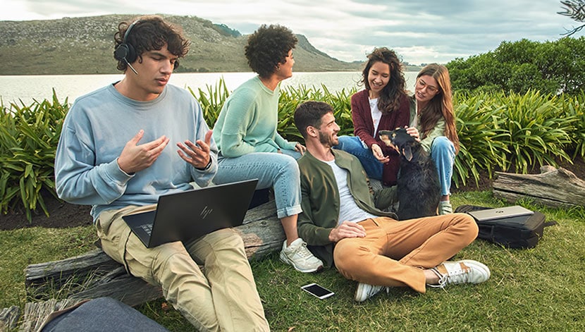 group of student sitting outside in a green area by a lake