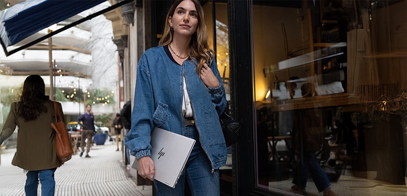 A woman walking with a HP laptop in her hand